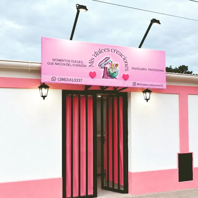 Frente de una pastelería con un cartel rosa iluminado y cortinas rosas en la puerta