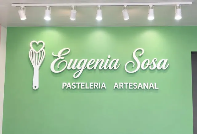 Letras corpóreas blancas con el nombre de una pastelería sobre una pared verde